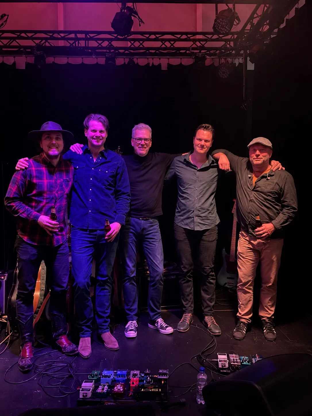 De vijf bandleden arm in arm op het podium van het Tromp Theater